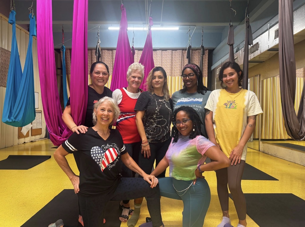 Clean Camp community members smiling together in the aerial yoga studio